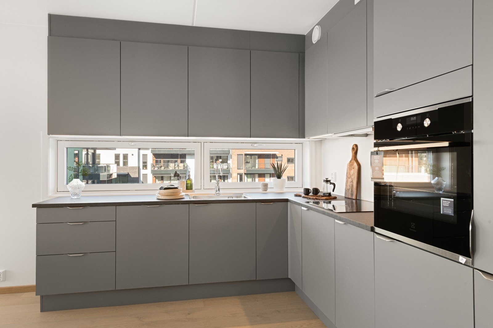 Hyggelig utsyn fra kjøkkenvinduet mellom kjøkkenbenk og overskap Galleribilde