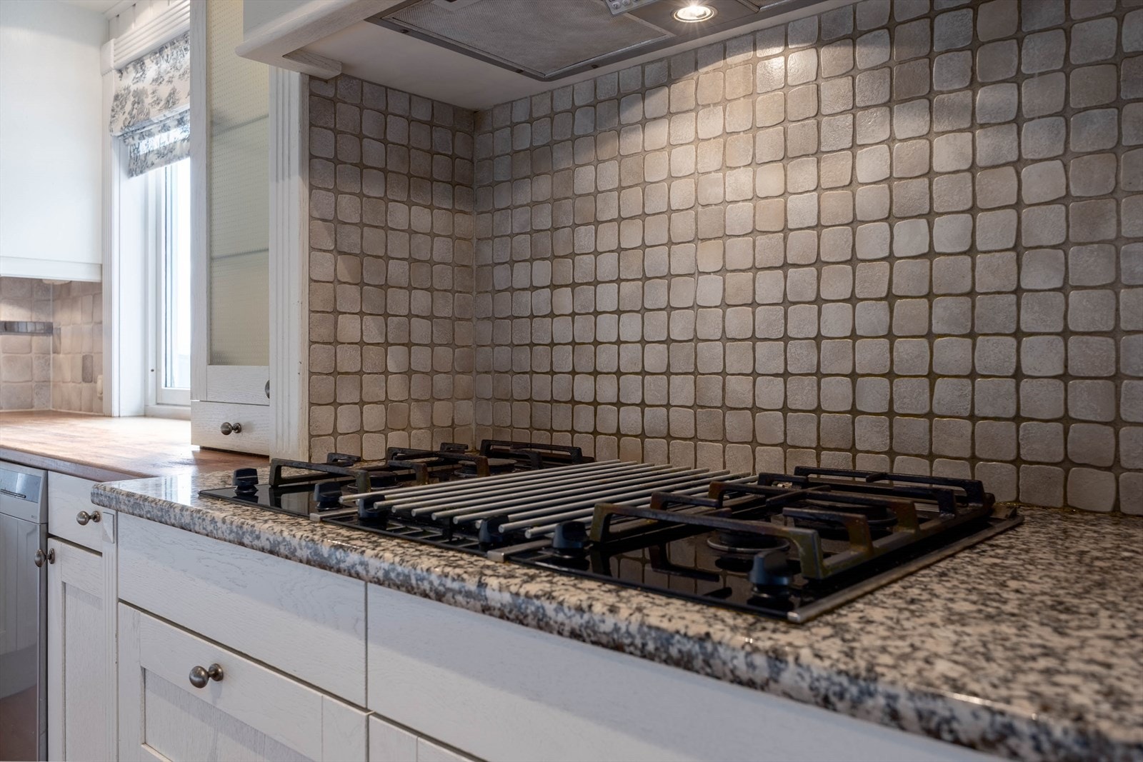 Moderne kjøkken med stilfulle fliser og integrert gasskomfyr, perfekt for matlaging med stil og funksjonalitet. Galleribilde