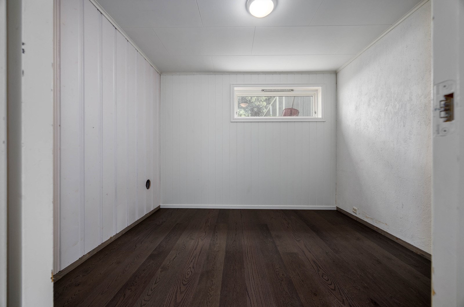 Lyst og funksjonelt rom med mørkt gulv, perfekt for kontor/arbeidsplass i underetasjen. Galleribilde