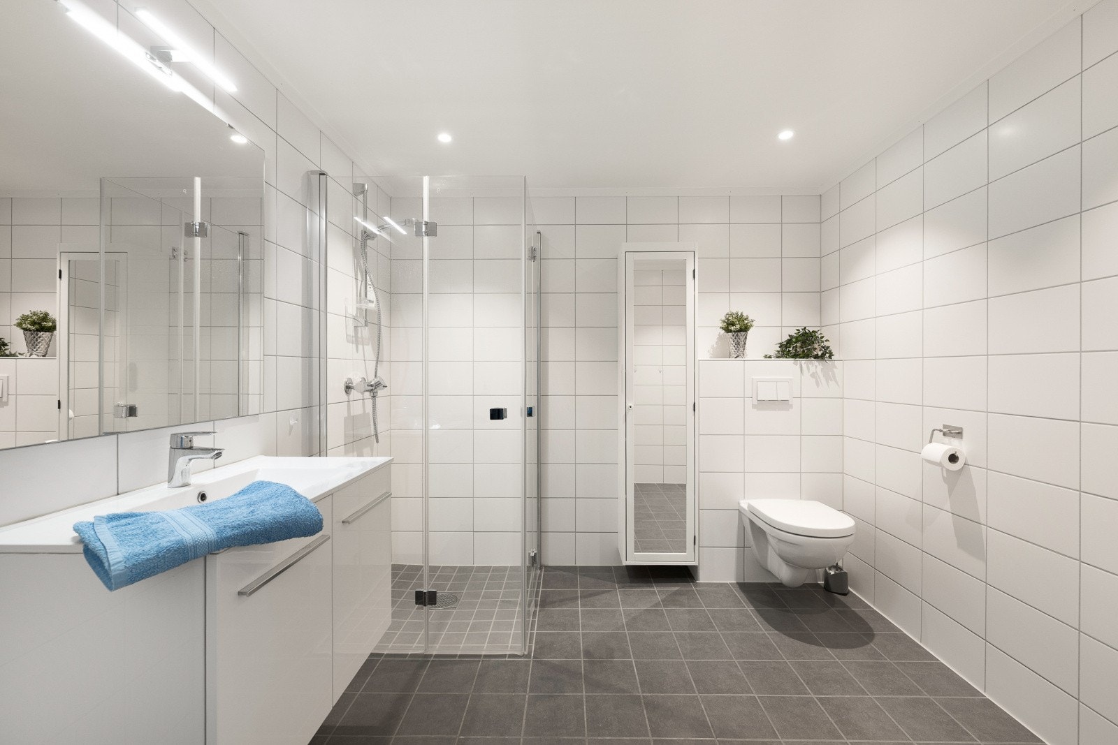 Badet har innredning med glatte fronter, vask m/ ettgrepsarmatur, dusjhjørne, vegghengt toalett og opplegg for vaskemaskin. Galleribilde