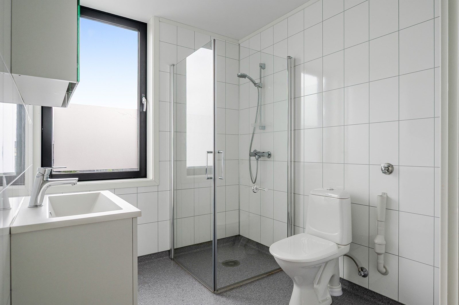 Badet har vamekabler i gulvet, hjørnedusj, servant, toalett og opplegg for vaskemaskin. Galleribilde