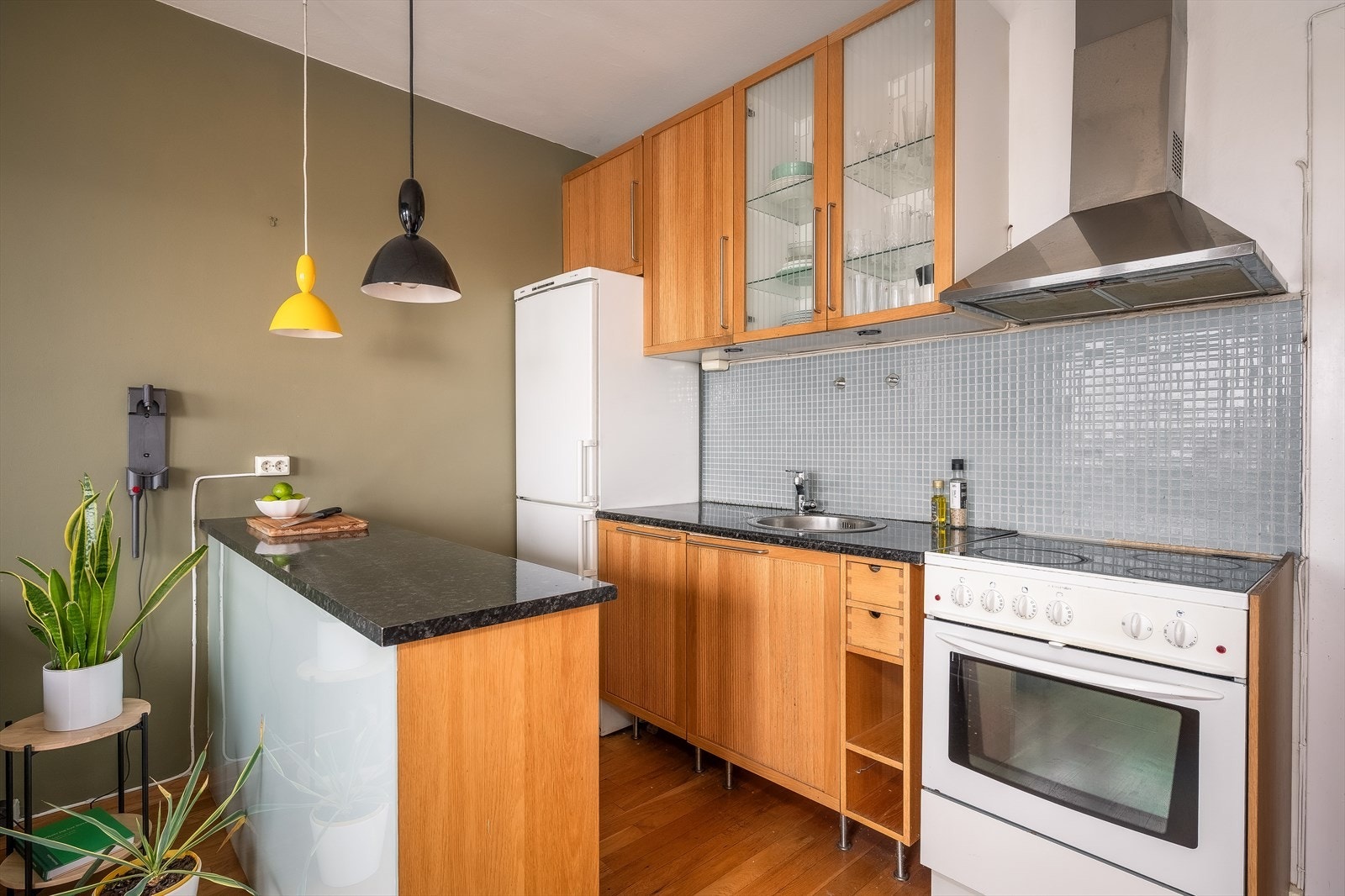 Kjøkken fronter av tre, mørk laminat benkeplate, innfelt rund vaskekum og frittstående hvitevarer. Galleribilde