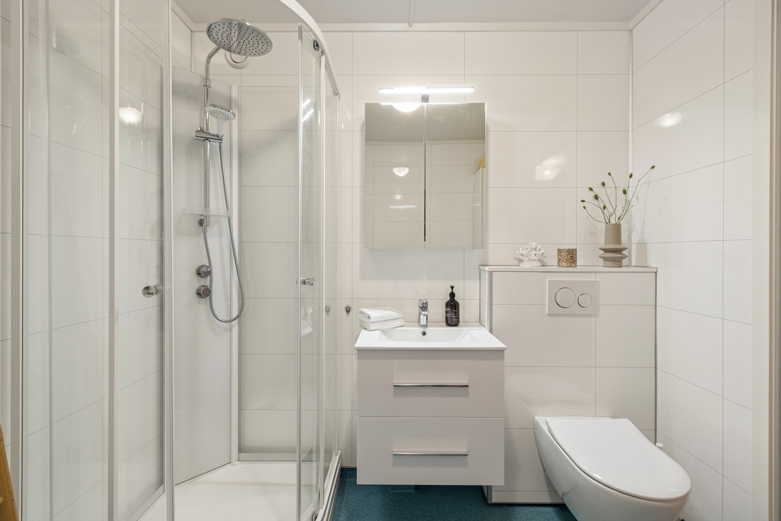 Baderom utstyrt med vegghengt wc, servant, speilskap og dusjkabinett. Vaskemaskin medfølger i salget. Mekanisk avtrekk. Galleribilde