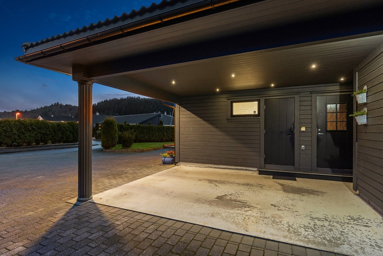 Carporten har betongdekke, belegningsstein i innkjørselen og integrert belysning i taket. Galleribilde