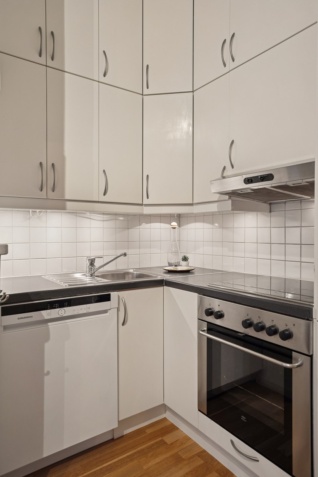 Kjøkkenet har over- og underskap med folierte fronter, benkebeslag med nedfelt oppvaskkum og platetopp, samt mekanisk avtrekk med kullfilter over stekesonen. Galleribilde