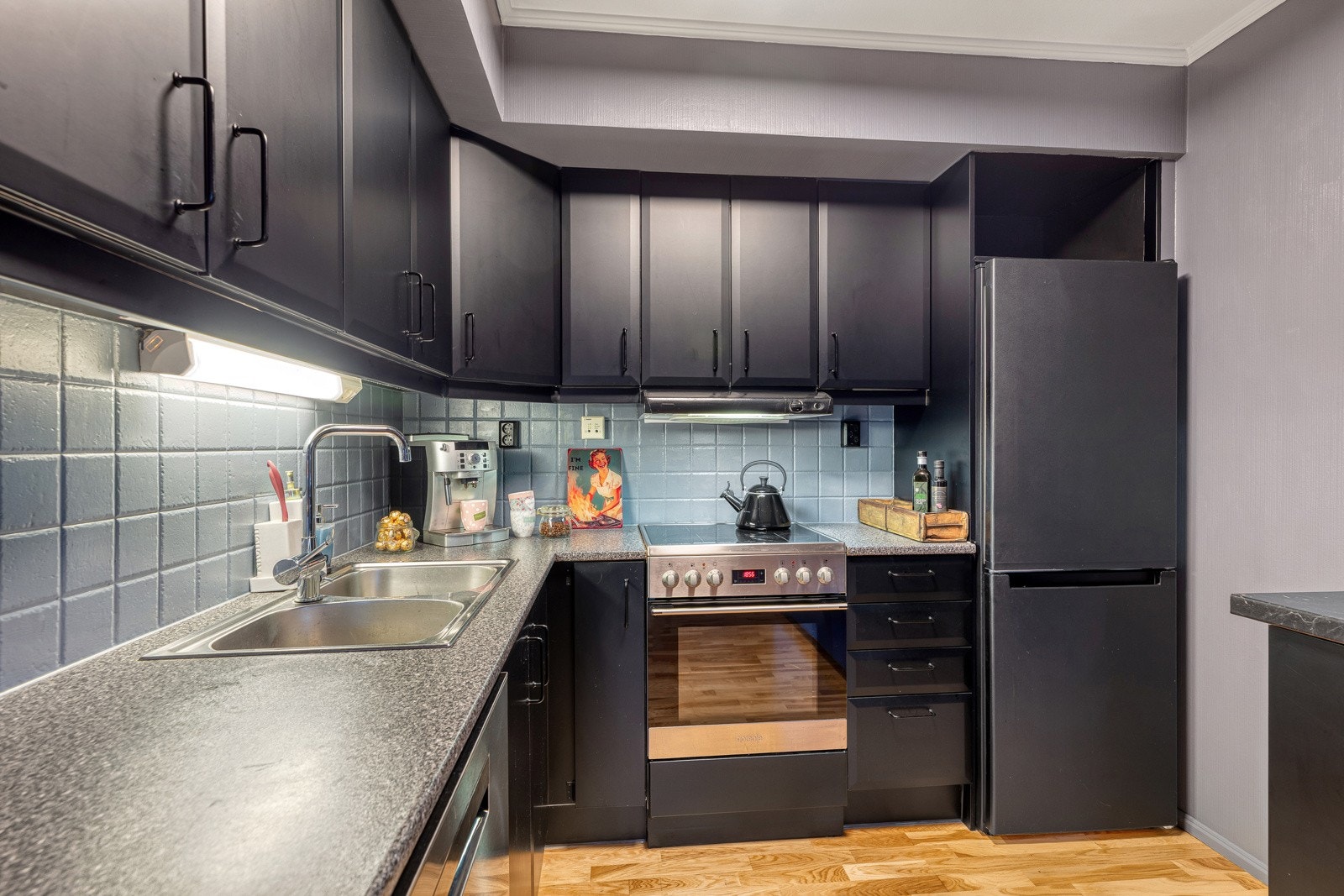 Mørkt laminert kjøkkeninnredning, fliser mellom over og underskap. Galleribilde