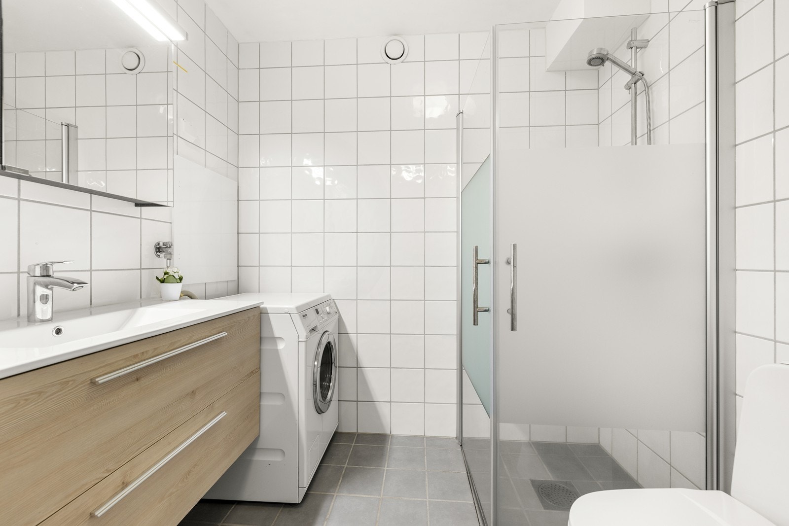 Helfliset bad med varmekabler i gulvet, vegghengt toalett og opplegg for vaskemaskin. Galleribilde