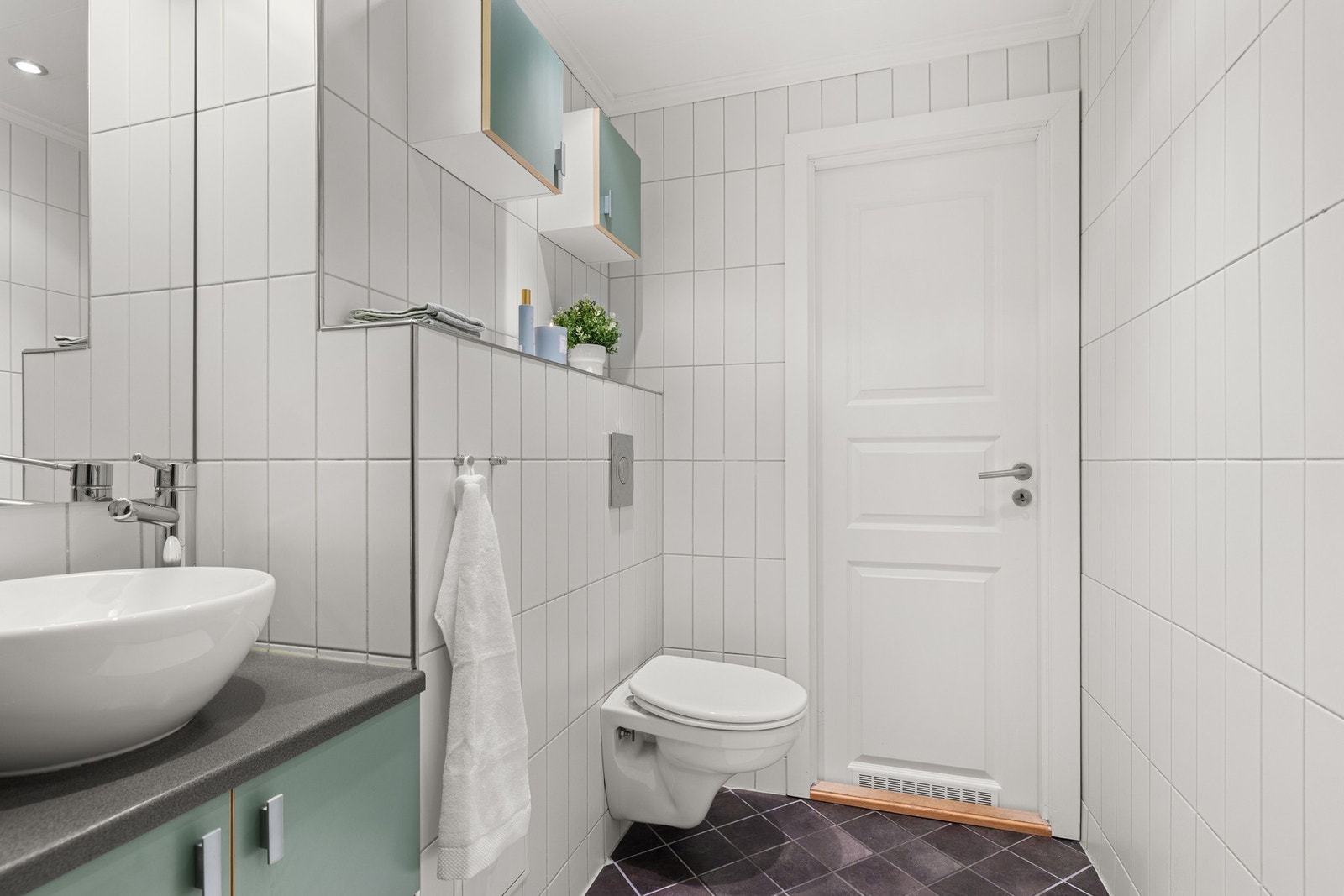 Varmekabler under flisene som styres med digital termostat montert på vegg ved dør. Galleribilde