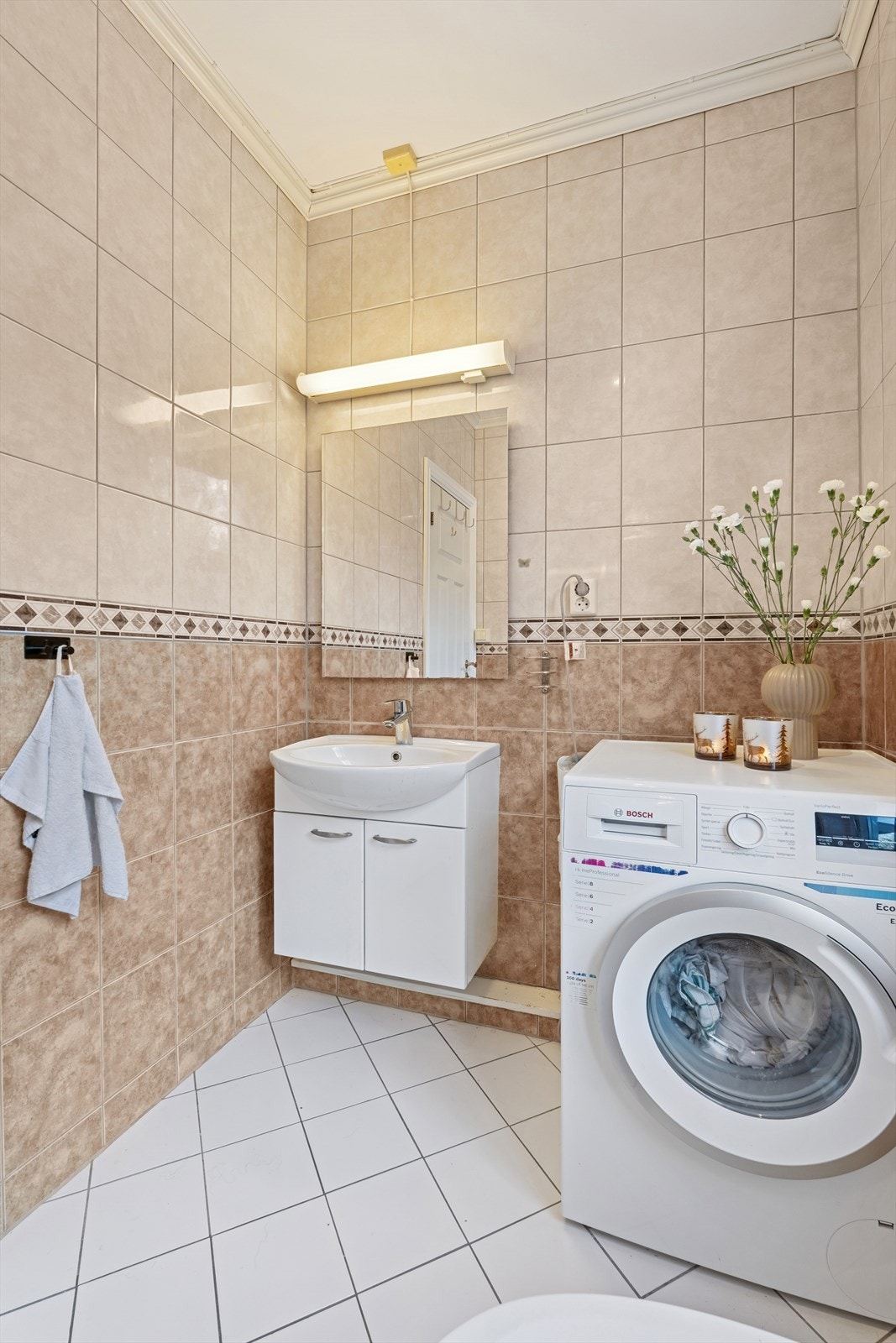 Badet i har flislagte vegger og gulv. Det er oppført med gulvstående toalett, dusjkabinett og opplegg til vaskemaskin. Galleribilde