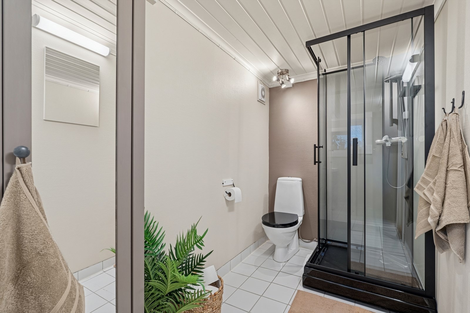 Badet er oppført med fliser på gulv og tapet på vegg. Galleribilde