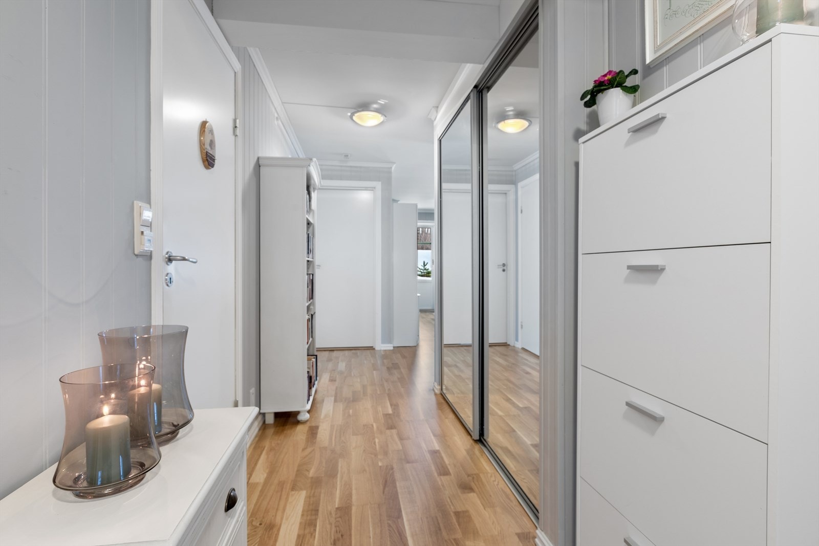 Lys entré med parkett på gulv og panelte overflater. Galleribilde