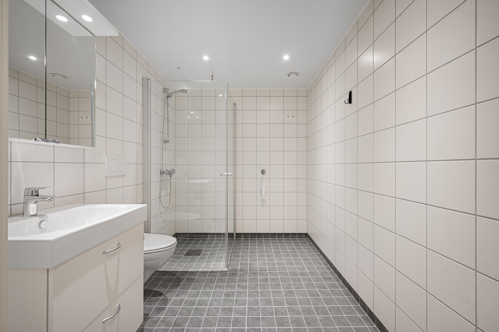 Moderne bad med med helfliset uttrykk og varmekabler som gir ekstra komfort Galleribilde