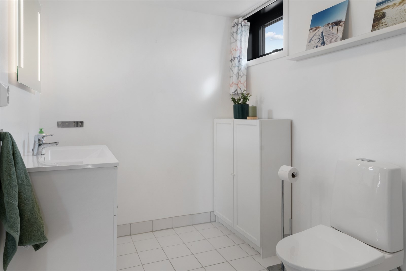 Badet er innredet med dusjnisje, gulvmontert toalett og hvit baderomsinnredning Galleribilde