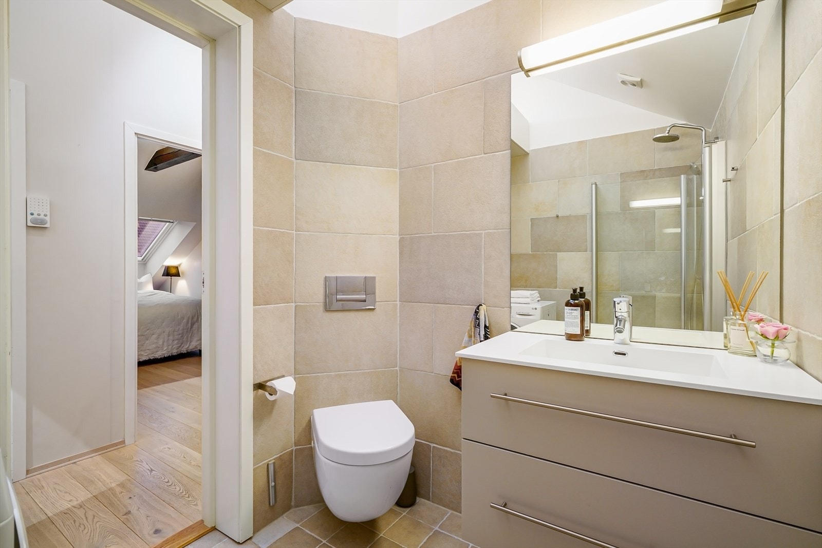 Badet er innredet med heldekkende servant på underskap med Corian benkeplate, speil med belysning og vegghengt toalett. Galleribilde