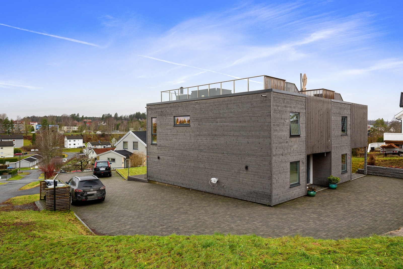 Stor steinbelagt gårdsplass med flere biloppstillingsplasser. Den steinbelagte gårdsplassen deles med naboenheten og gir et ryddig og tiltalende helhetsinntrykk. Galleribilde