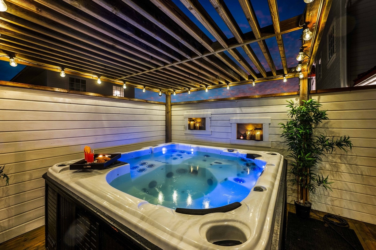 Ute på terrassen får du spafølelsen hjemme med jacuzzi under en hyggelig pergola Galleribilde