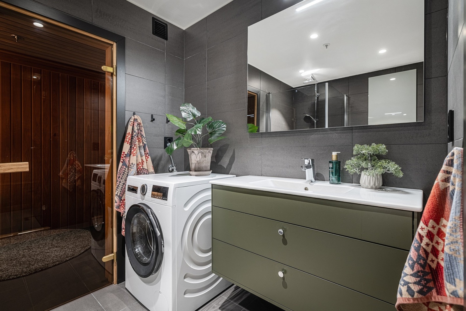 Baderomsinnredningen er stilren med skuffer, porselensservant og speil med integrert belysning, samt opplegg for vaskemaskin. Galleribilde