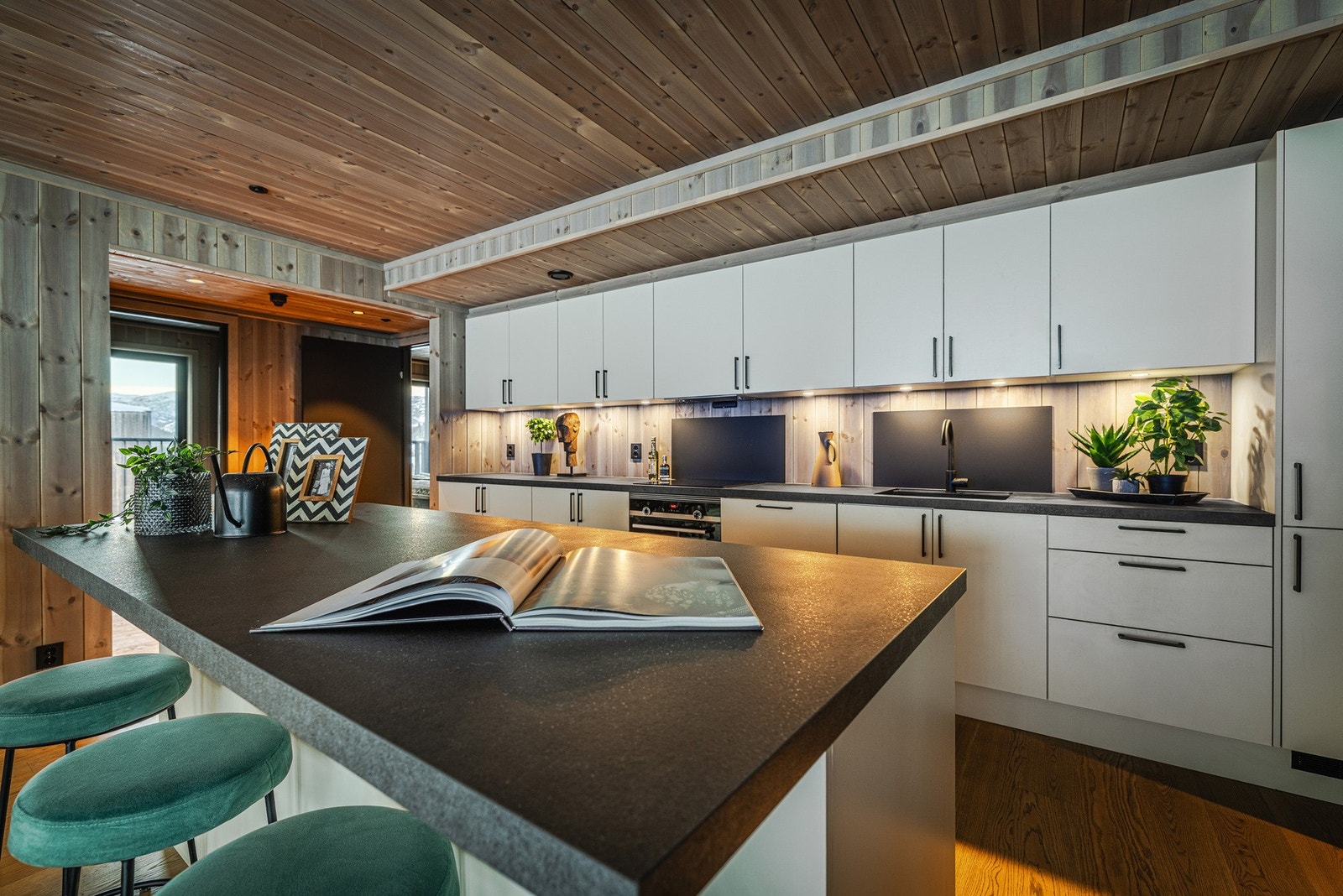 Kjøkkenet fremstår som moderne og stilrent med hvit innredning fra Sigdal, elegant kombinert med sorte dørhåndtak. Galleribilde