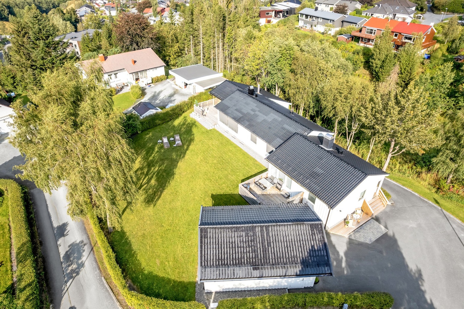 Oversiktsbilde som viser eiendommens romslige tomt, flotte plenarealer og praktisk innkjørsel. Galleribilde