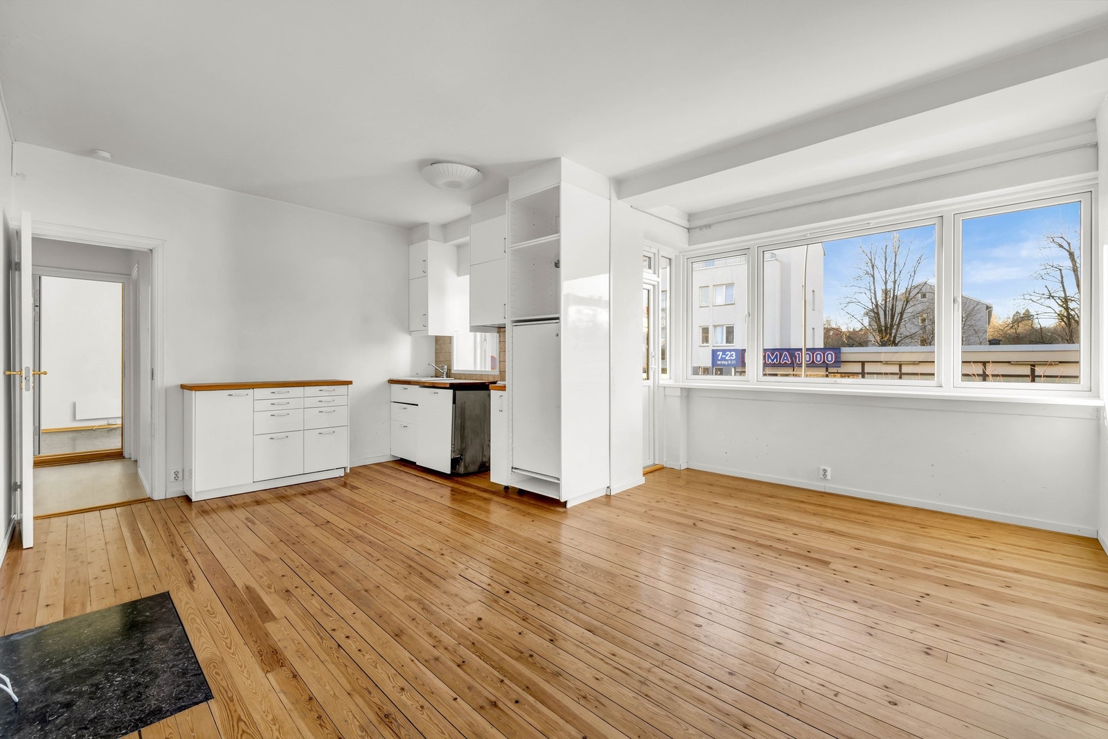 Stue og kjøkken er samlet i en romslig og lys åpen løsning som gir boligen et moderne og sosialt preg. Her er det god plass til både spisebord og sofagruppe, med naturlig soneinndeling som gjør rommet enkelt å innrede. Galleribilde