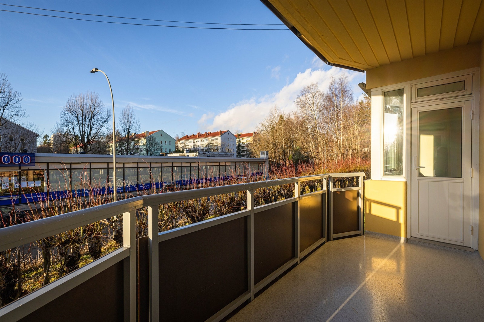På sommeren er balkongen skjermet av en grønn hekk mot bebyggelsen vis a vis Galleribilde