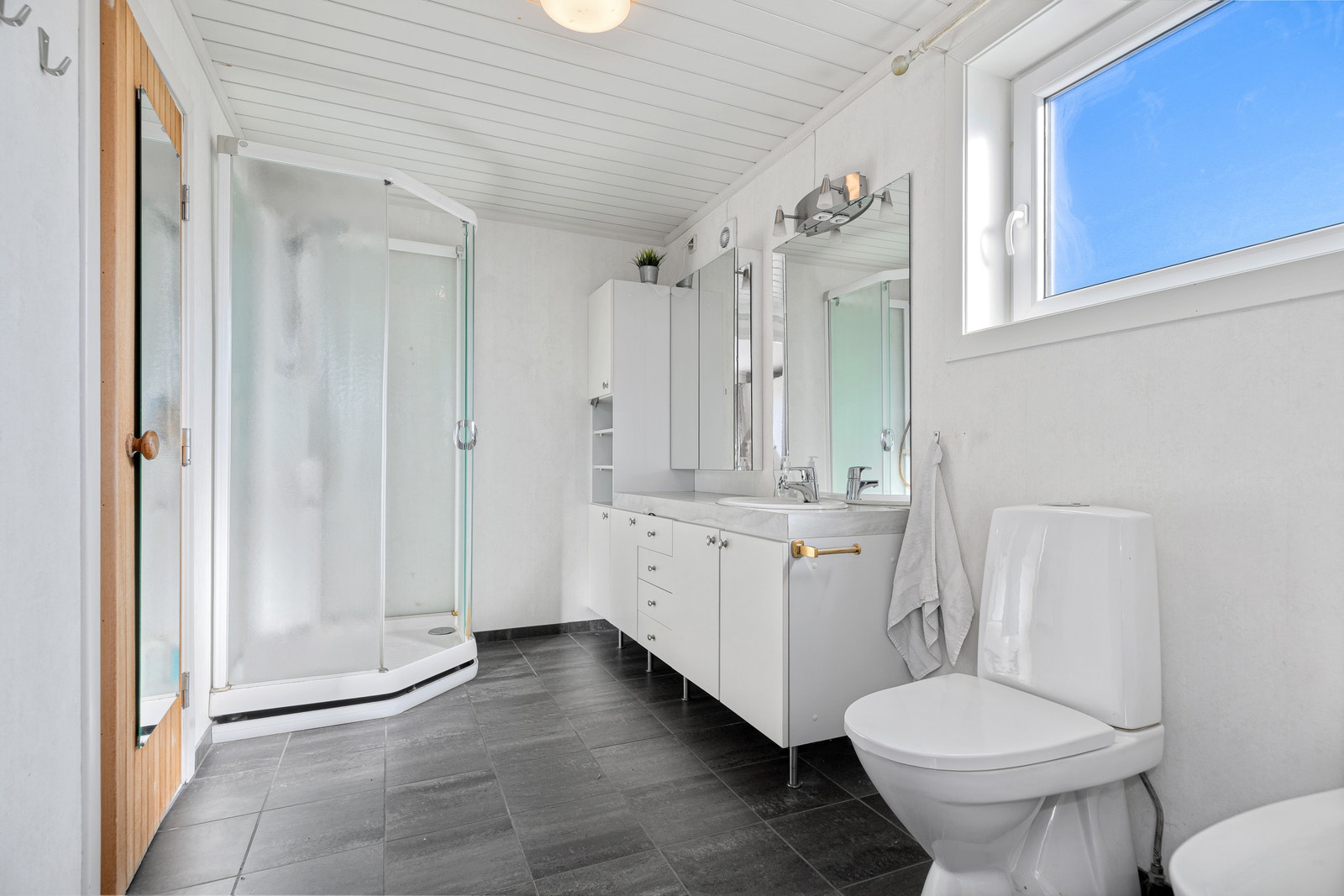 Hovedbad med dusjkabinett, wc, baderomsinnredning og vindu. Galleribilde