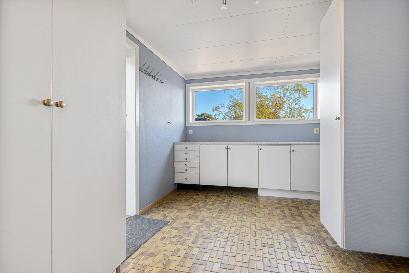 Vaskerom/bod med skapinnredning, knaggrekke og vindu. Galleribilde