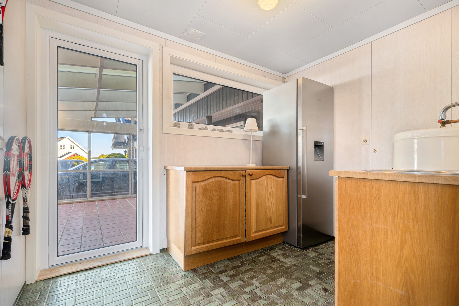 Grovinngang med kjøleskap/fryser, skap og utgang til uteplass. Galleribilde