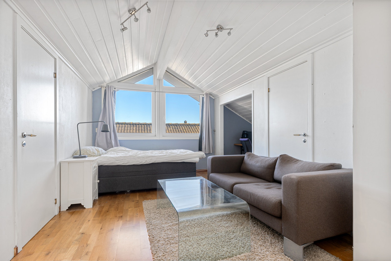 Romslig soverom med seng, sofa, salongbord og parkett. Galleribilde