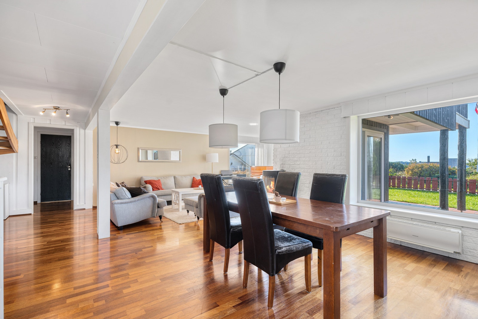 Spisestue i åpen løsning mot stue, med store vinduer og parkettgulv. Galleribilde