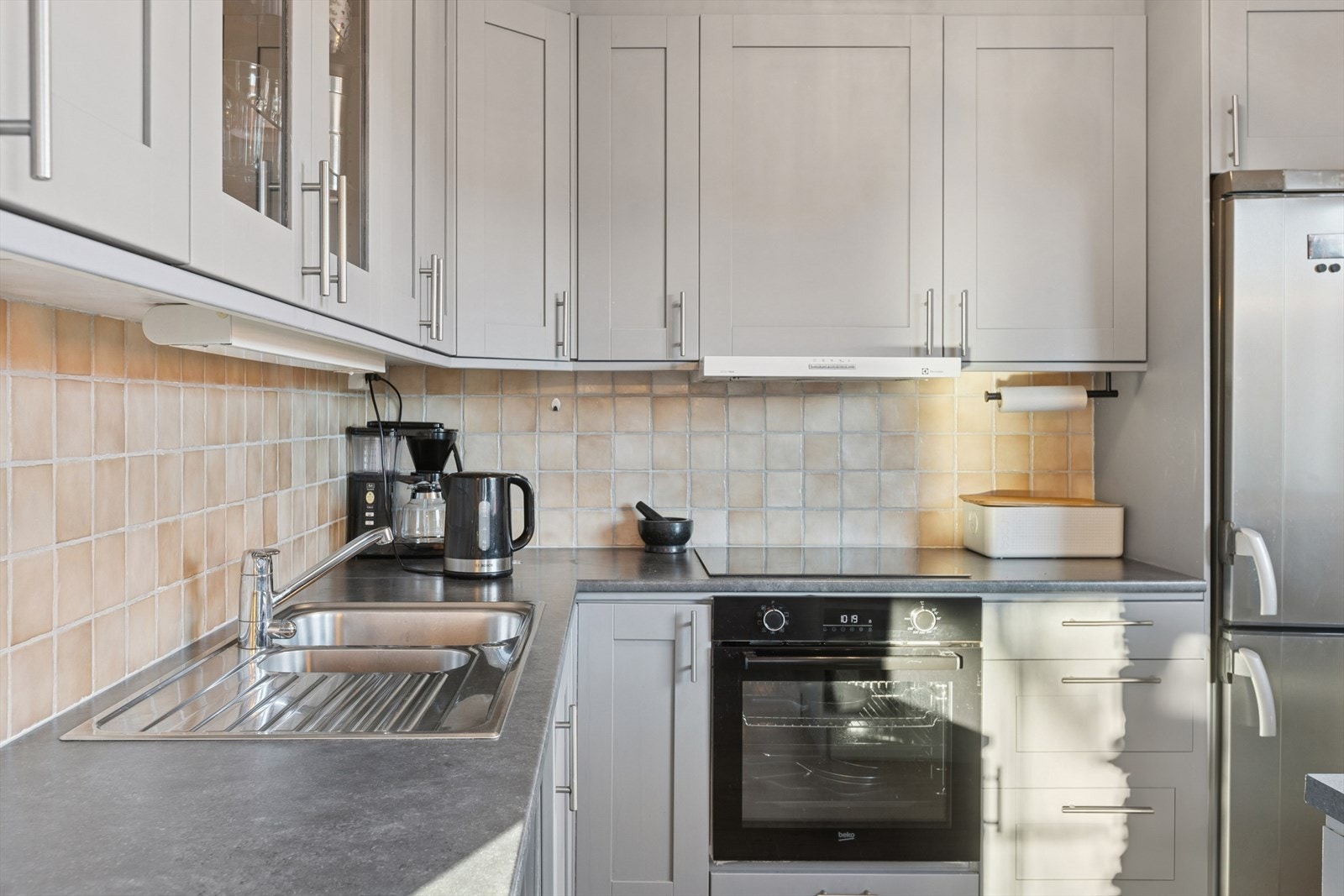 Kjøkkenet fra 2006 har en innredning med grå profilerte fronter, laminert benkeplate og ståkum med ett-greps blandebatteri. Galleribilde