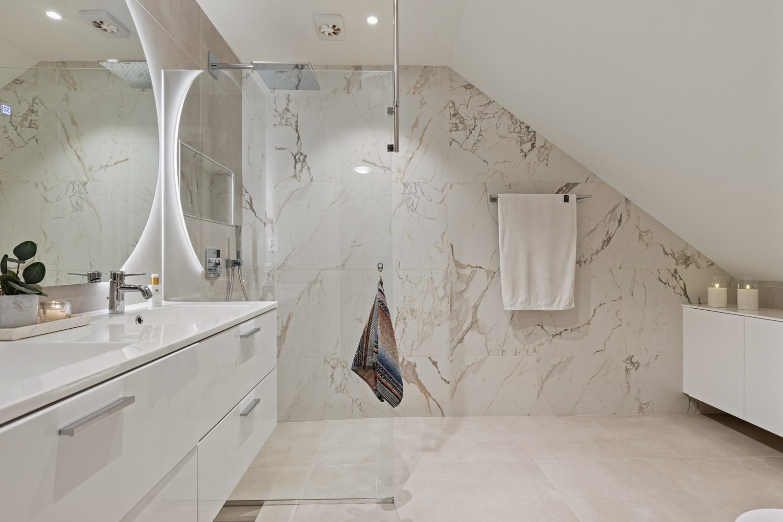 Innredet med dobbel servant, veggmontert toalett og dusjhjørne med glassvegger. Elektrisk styrt vifte gir effektiv ventilasjon. Galleribilde