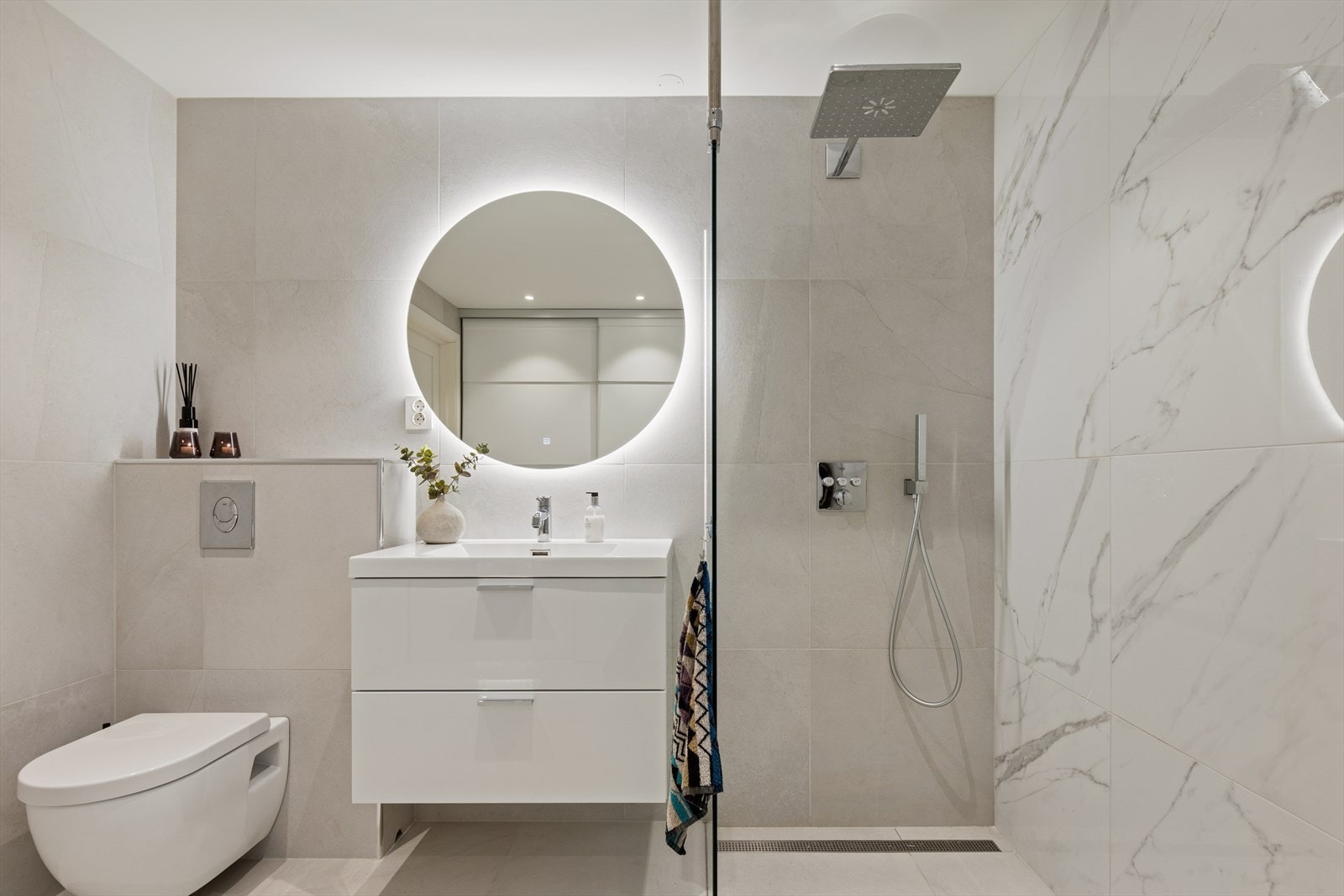 Rommet har innredning med nedfelt servant, veggmontert toalett, dusjhjørne med glassvegger. Galleribilde