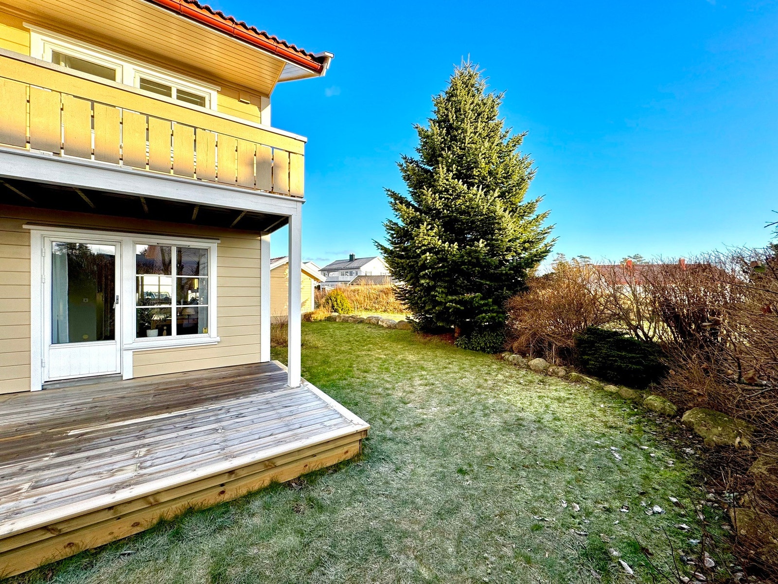 Terrasse og hage. Opparbeidet variert beplantning rundt tomten skjermer fint mot naboeiendommer. Galleribilde