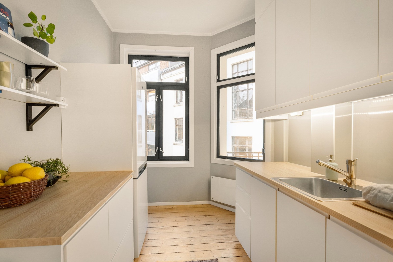 På kjøkkenet er det stilrene hvite matte fronter som er håndtaksfrie. Benkeplatene er i laminat med tre-mønster. Galleribilde