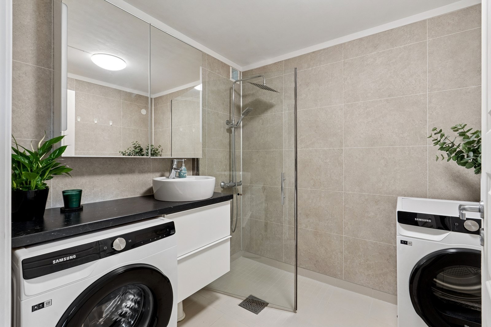 Lekkert bad med plass for vaskemaskin og tørketrommel. Dusj i hjørne. Pen servant med skuffer under og speilskap. Galleribilde