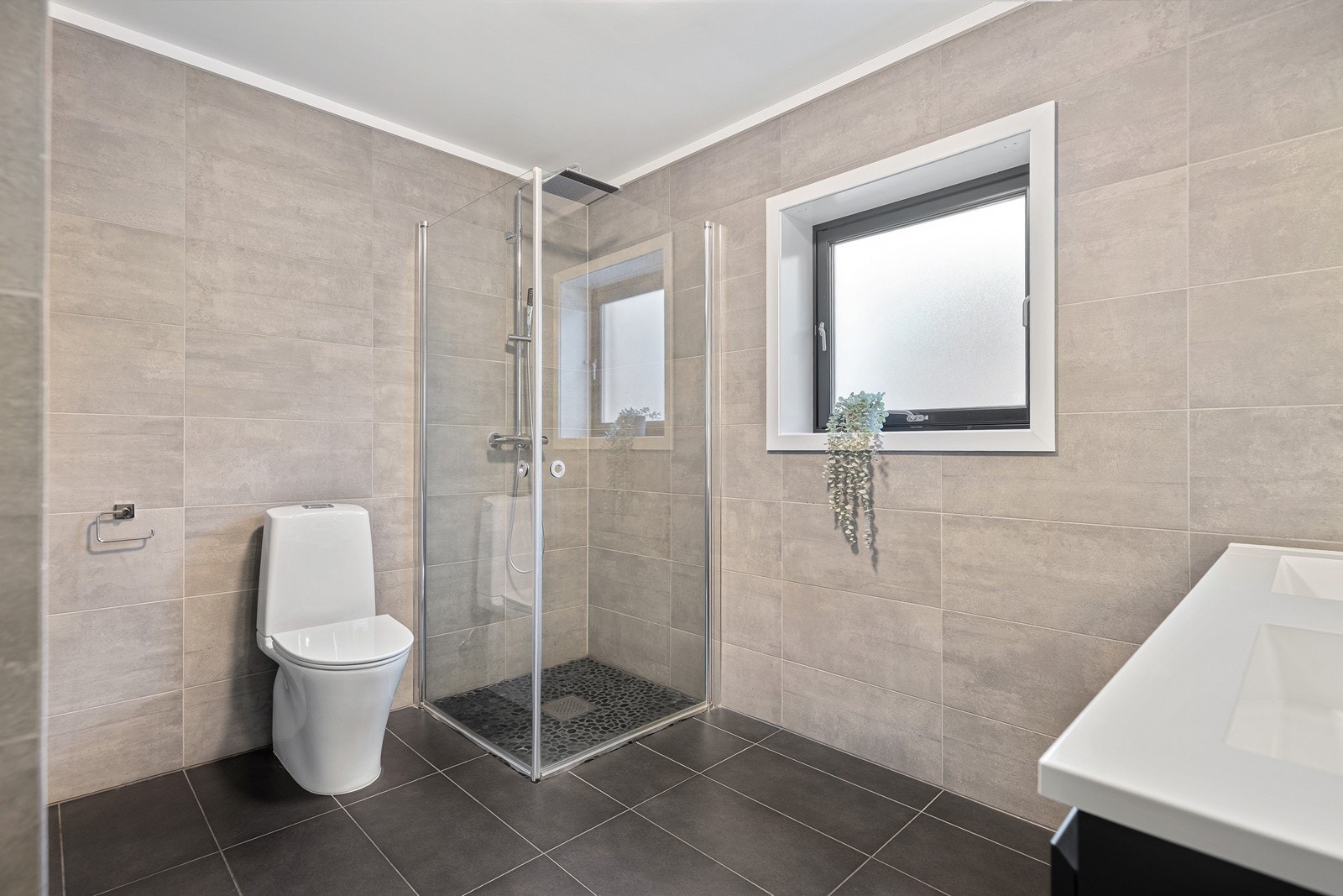 Flott baderom bestående av toalett, dusjhjørne og baderomsinnredning Galleribilde