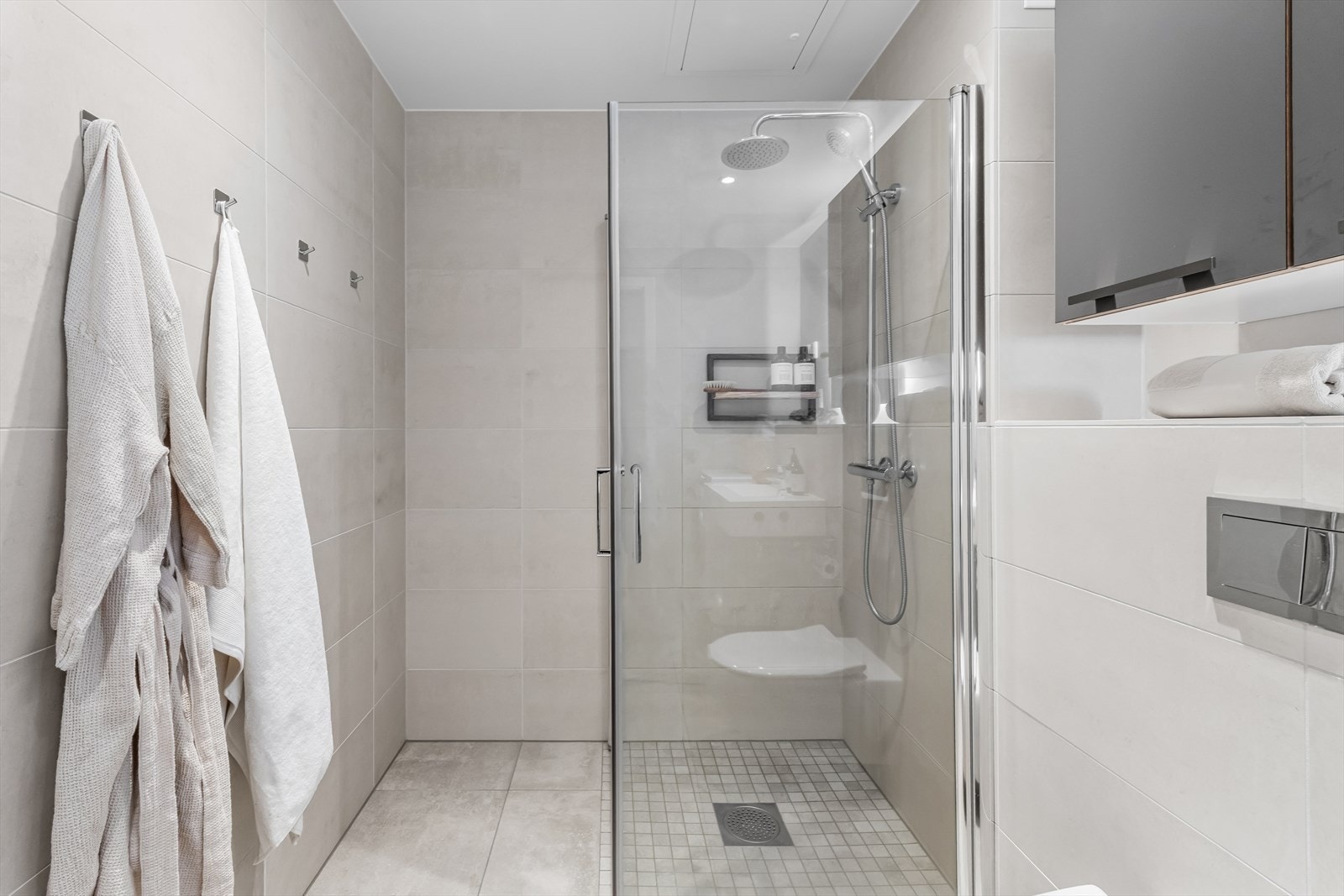 Badet er utstyrt med heldekkende servant, speil med belysning, vegghengt toalett og dusj med herdet glassdører. Galleribilde