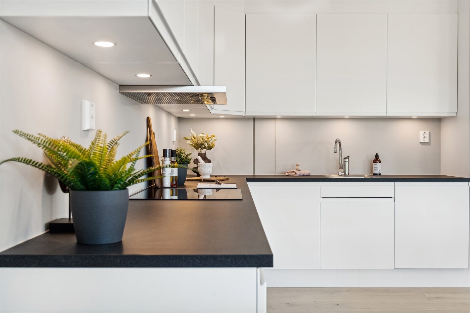 Kjøkken med hvite glatte fronter og mørk laminert benkeplate Galleribilde