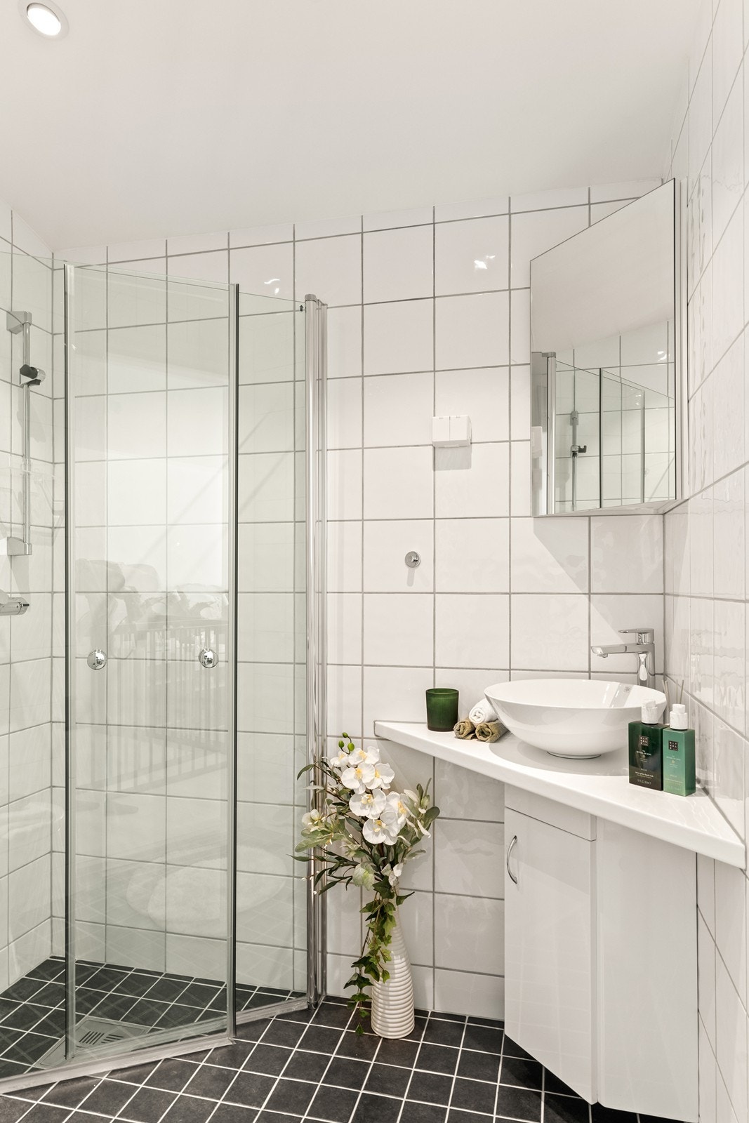 Helfliset baderom i andre etasje med enkel servant og dujsnisje med sammenleggbare dører i glass Galleribilde