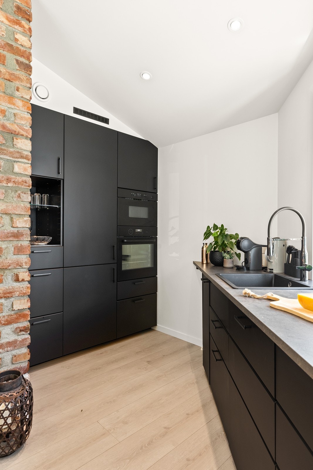 Et moderne og innebygget kjøkken i med sorte slette fronter og integrerte hvitevarer Galleribilde