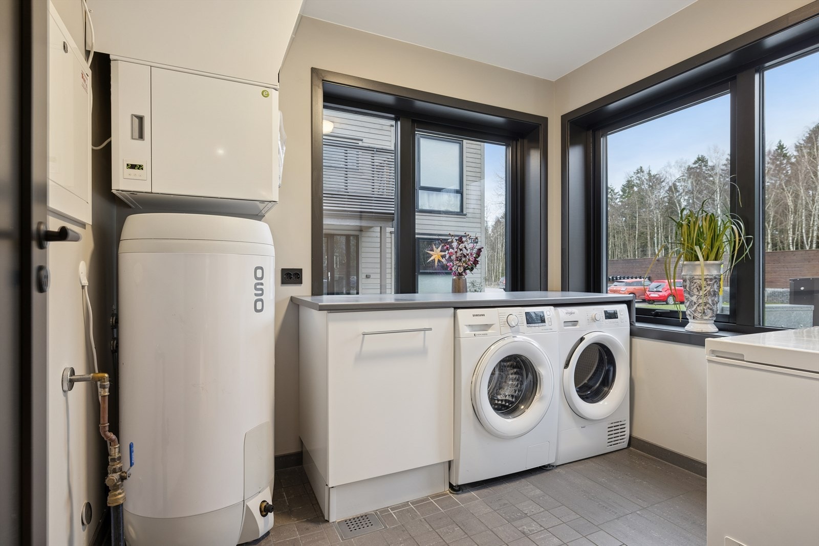 Vaskerommet er gjennomtenkt for maksimal funksjonalitet og komfort. Gulvvarme gir en behagelig temperatur året rundt, og den dedikerte vaskeromsdelen er utstyrt med solid benkeplate som gir god arbeidsflate. Galleribilde