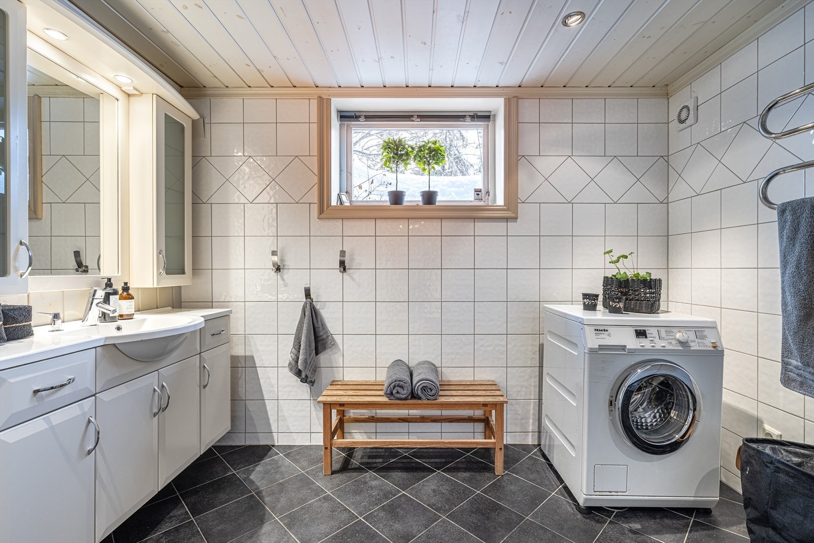 Delikat baderom i tidsriktige grå og hvite toner med opplegg for vaskemaskin. Galleribilde