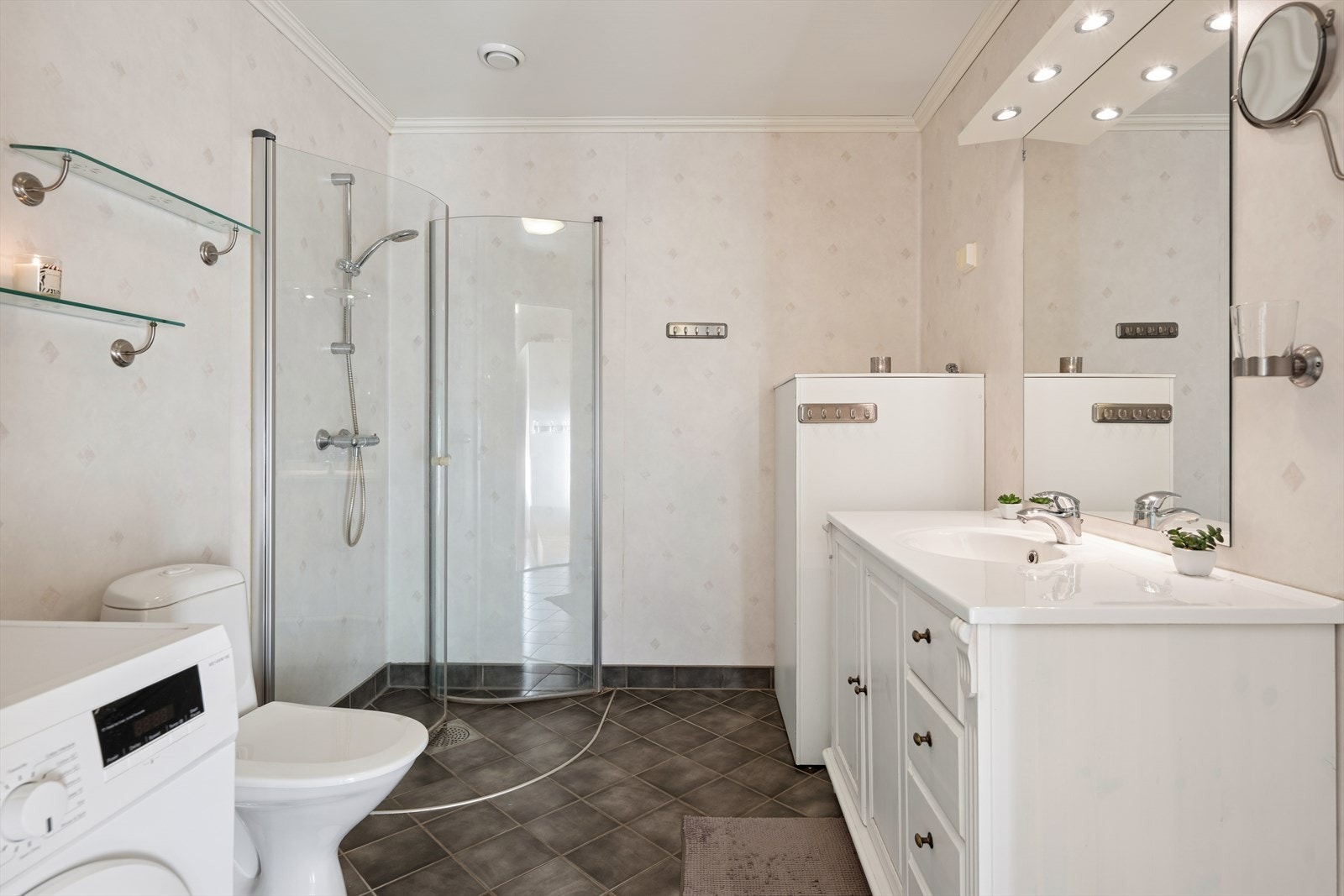 Baderommet har flislagt gulv med elektriske varmekabler. Her er innfellbare dusjvegger, servant med skapinnredning og opplegg for vaskemaskin. Galleribilde