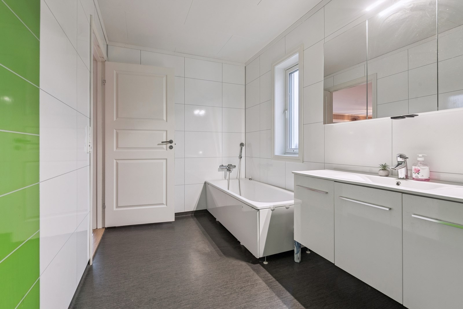 Bad i 1. etasje med vinylbelegg med varme i gulvet og våtromsplater på veggene. Galleribilde