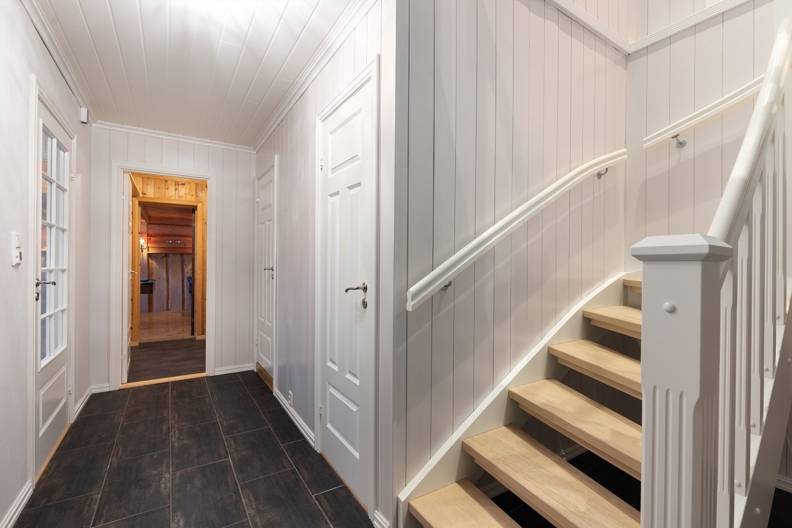 Boligen har lyse gangarealer med varmekabler i gulvet. Herfra er det åpen malt trapp med eik i trinna opp til hovedetasjen. Galleribilde