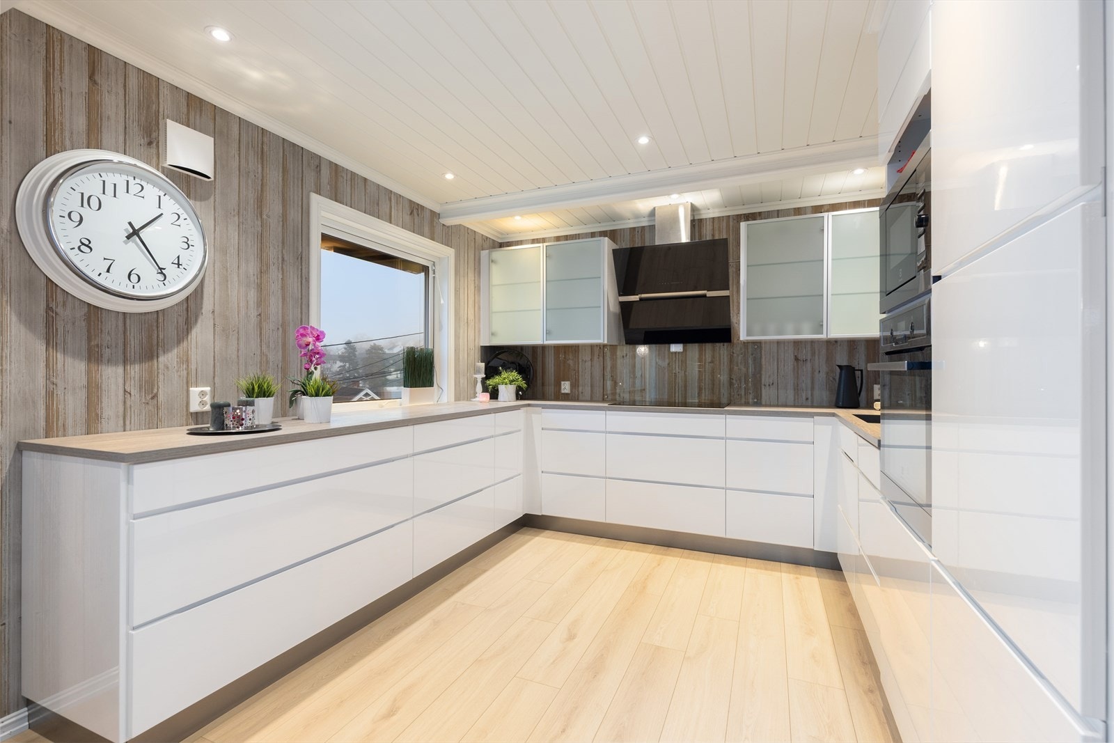 Det delikate kjøkkenet har innredning med høyglans fronter og overskap med frostet glass. Kjøkkenet har et lett og avslappet uttrykk, med både overskap og åpen veggplass, samt vindu som tilfører godt arbeidslys til benkeflatene. Galleribilde