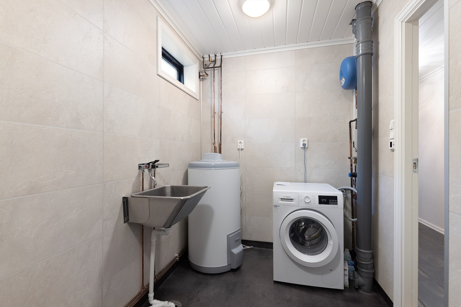 Vaskerommet er renovert i 2022 etter vannskade og har belegg på gulv med varmekabler. Det praktiske rommet er av god størrelse, med skyllekum og opplegg for vaskemaskin. Galleribilde