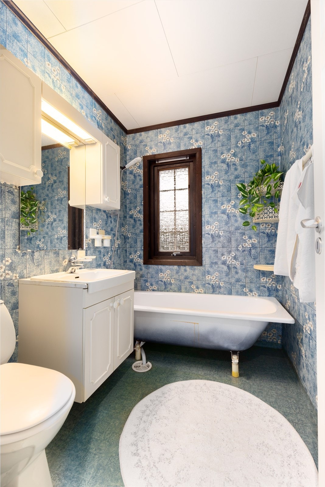 Badet i hovedetasjen har belegg på gulv med varmekabler. Badet av eldre dato er innredet med servantskap, overskap med speil, badekar med dusjgarnityr og toalett. På veggoverflatene er det våtromstapet. Galleribilde