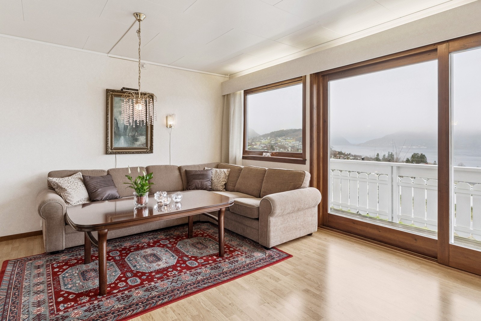 Store vindaugsoverflater slepp inn rikeleg med dagslys, og tek landskapet inn i stova Galleribilde